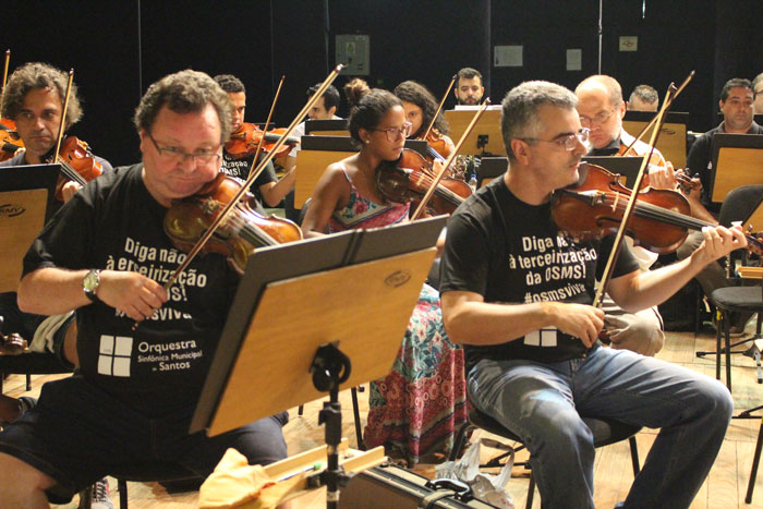 Músicos tocando no Teatro Coliseu. Todos com a camisa que diz: "Diga não à terceirização da OSMS! #osmsviva"